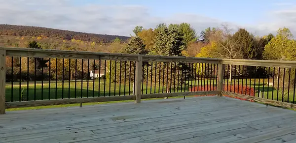 Wood deck with black baluster railing overlooking a mountain valley