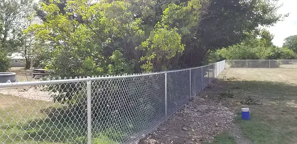 Long galvanized chainlink fence defining a residential property boundary