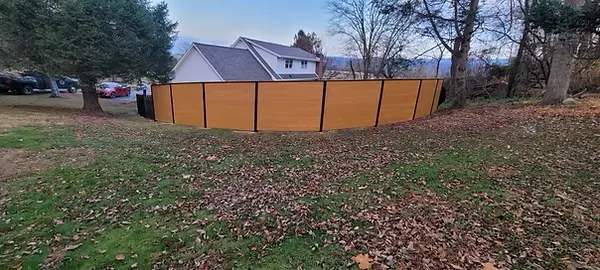 Curved run of stained wood fence panels with black metal framing
