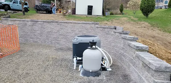 Stepped gray retaining wall surrounding a residential pool installation