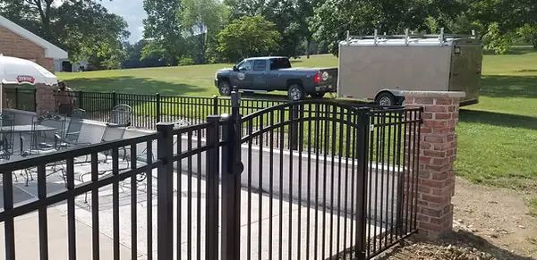 Brick pillars framing a black aluminum gate beside a patio