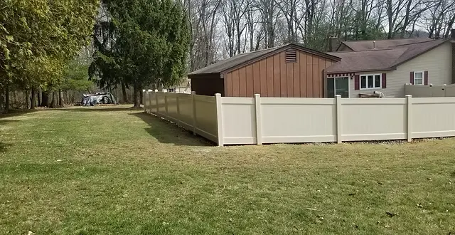 Tan vinyl privacy fence enclosing a large residential yard