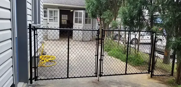 Black chainlink double gate installed beside a home