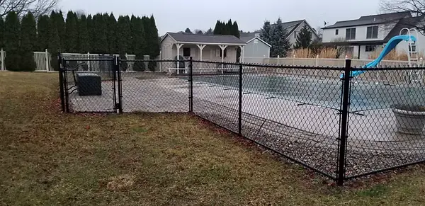 Black chainlink fence and gate enclosing a backyard pool
