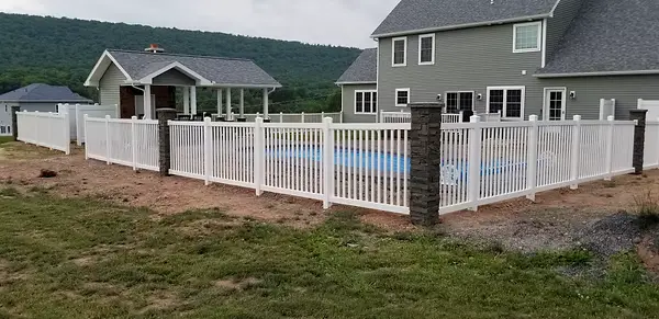 Stone pillars integrated with a white pool fence surrounding a residential pool