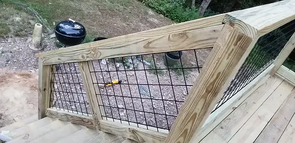 Angled deck stair railing framed in wood with black hog wire panels