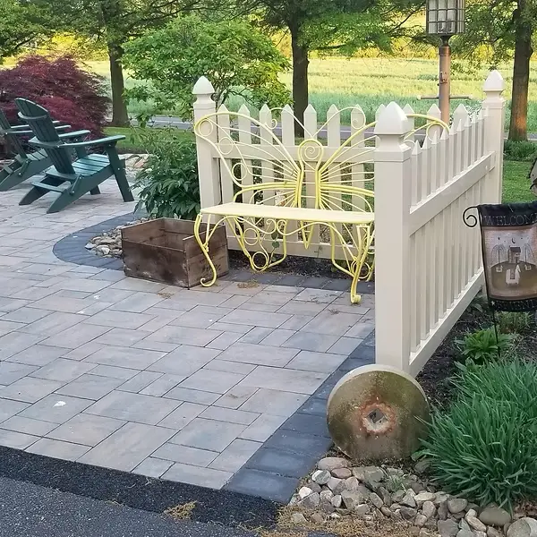 White vinyl picket fence beside a paved garden sitting area