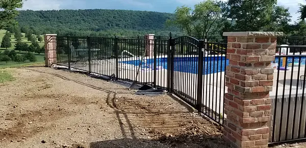 Brick entrance pillars integrated with a black pool fence and gate