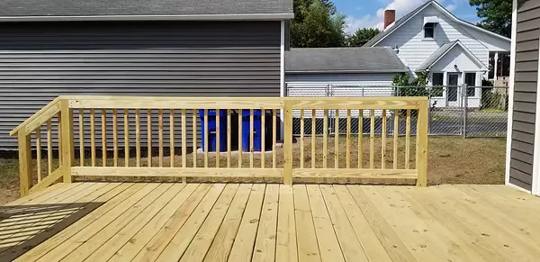 Treated wood deck railing with square pickets in a backyard setting