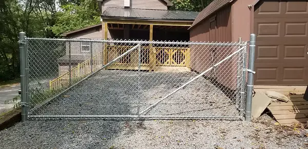 Wide galvanized chainlink double gate across a residential driveway
