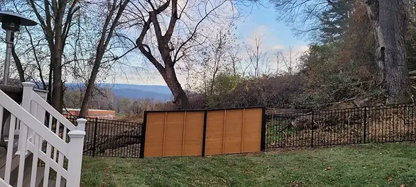 Stained wood fence panels with black metal framing across a backyard